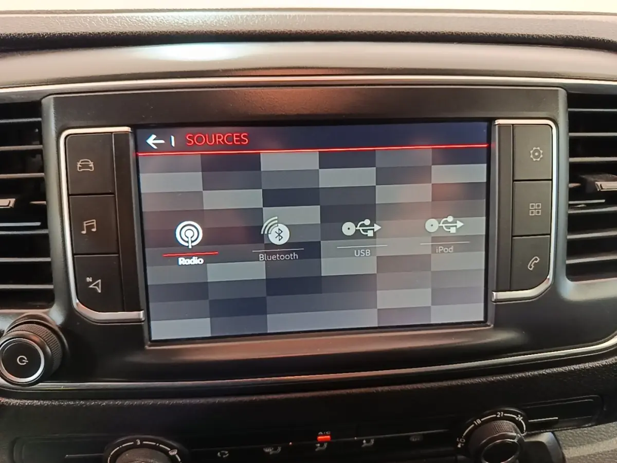 Écran tactile central du tableau de bord du Citroën Jumpy blanc, affichant les sources audio radio, Bluetooth, USB et iPod.