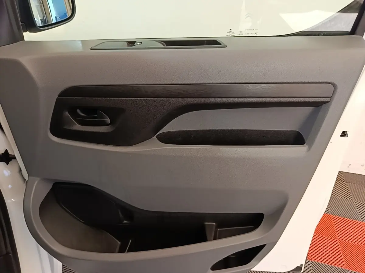 Vue rapprochée de la porte intérieure côté gauche du Citroën Jumpy XS blanc, avec poignée et rangements intégrés.