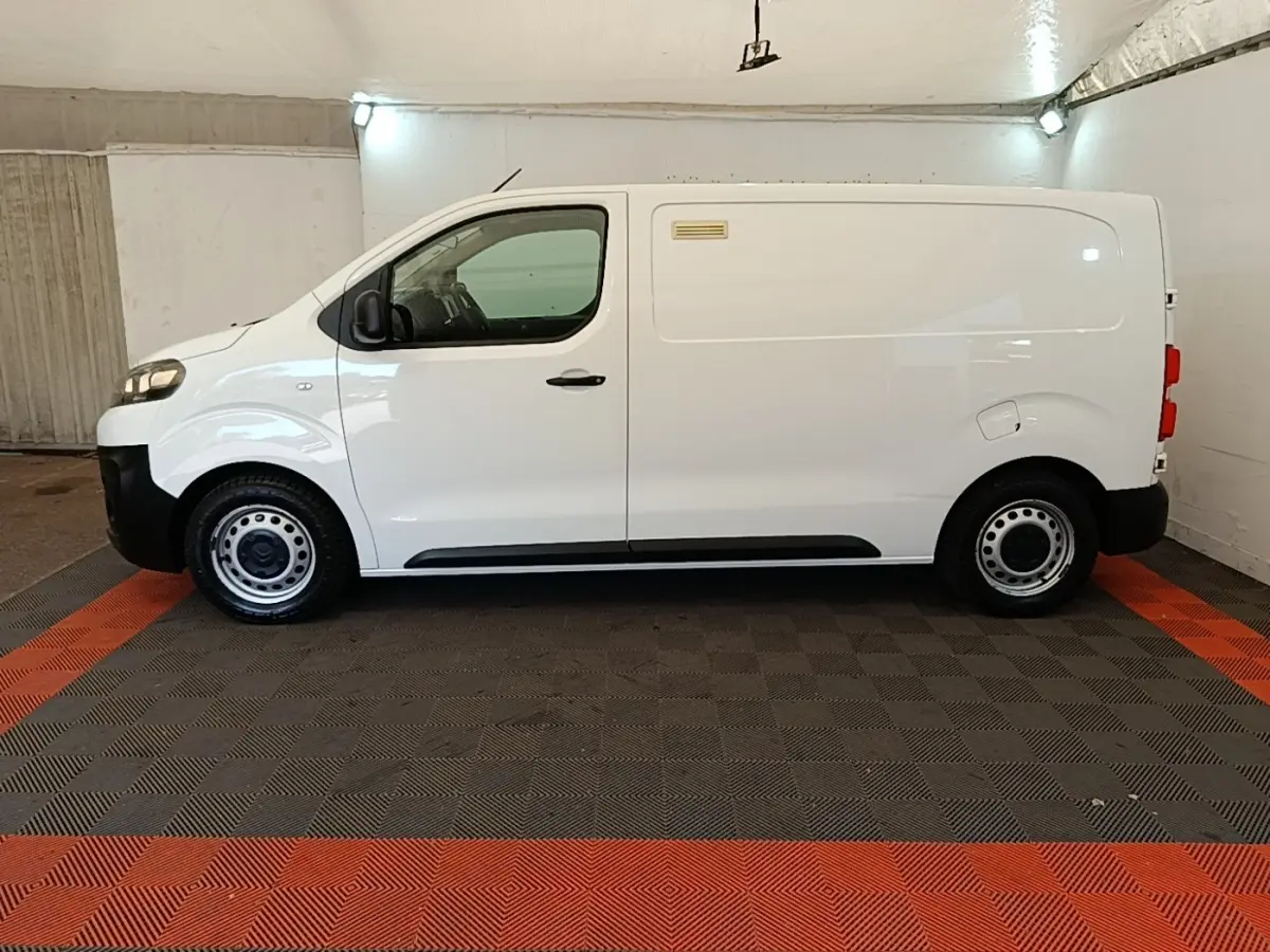 Vue de profil côté gauche d’un utilitaire Citroën Jumpy XS BlueHDi 120 blanc, roues acier et pare-chocs noirs.