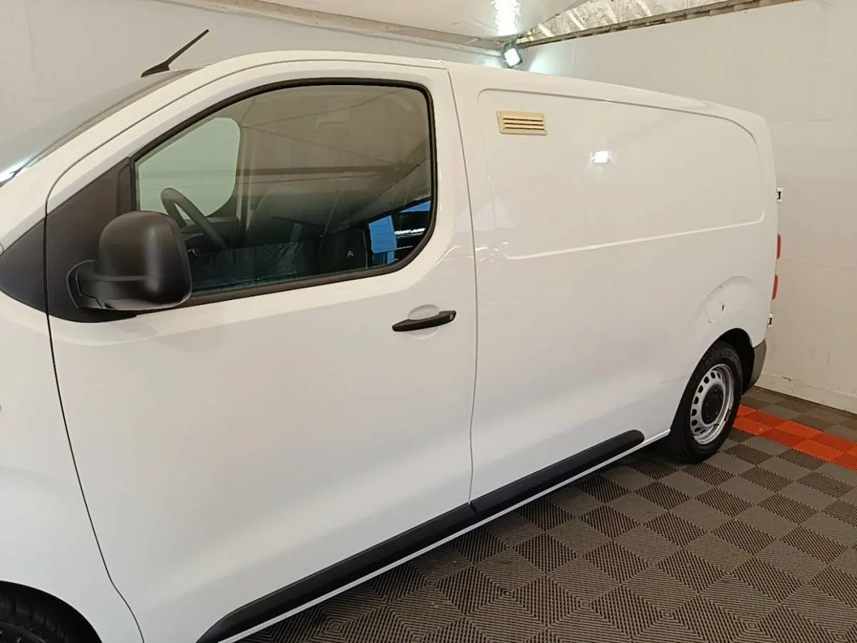 Vue de profil côté gauche d’un utilitaire Citroën Jumpy blanc, avec porte latérale pleine et jantes acier.
