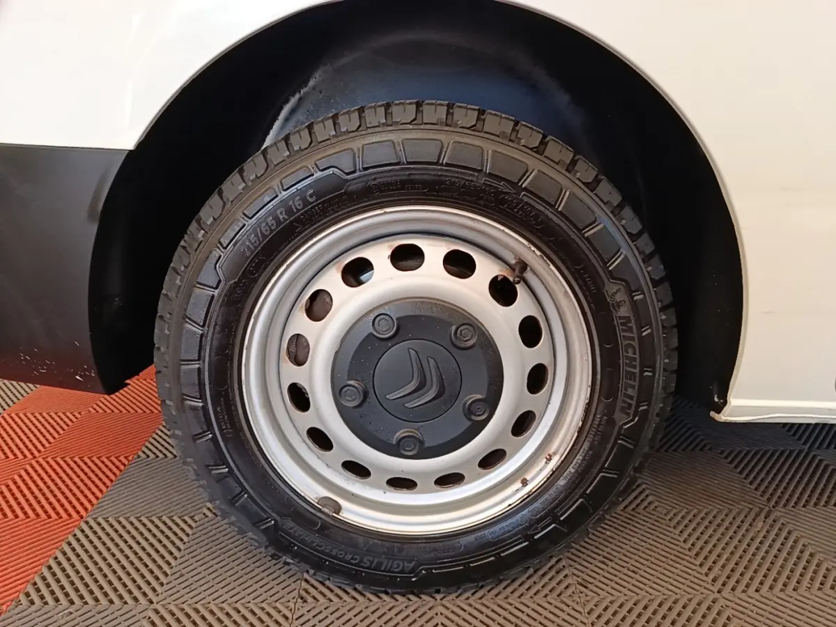 Gros plan sur la roue avant droite acier avec logo Citroën, sur fond de carrosserie blanche du Citroën Jumpy XS.