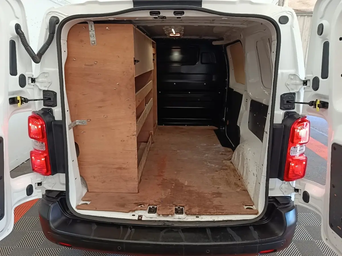 Vue arrière ouverte du Citroën Jumpy blanc montrant l’espace de chargement avec étagères en bois à gauche.