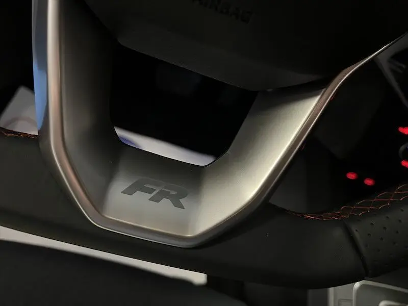 Gros plan sur le volant noir avec surpiqûres orange et logo FR de la SEAT IBIZA 1.5 TSI 2024.
