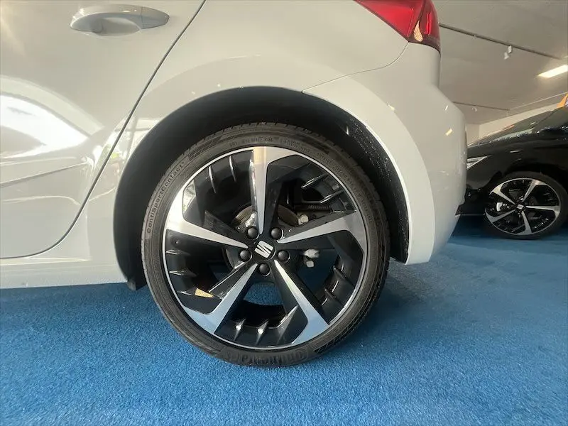 Gros plan sur la roue arrière gauche d'une SEAT Ibiza blanche Nevada Metal avec jante alliage bicolore en concession.