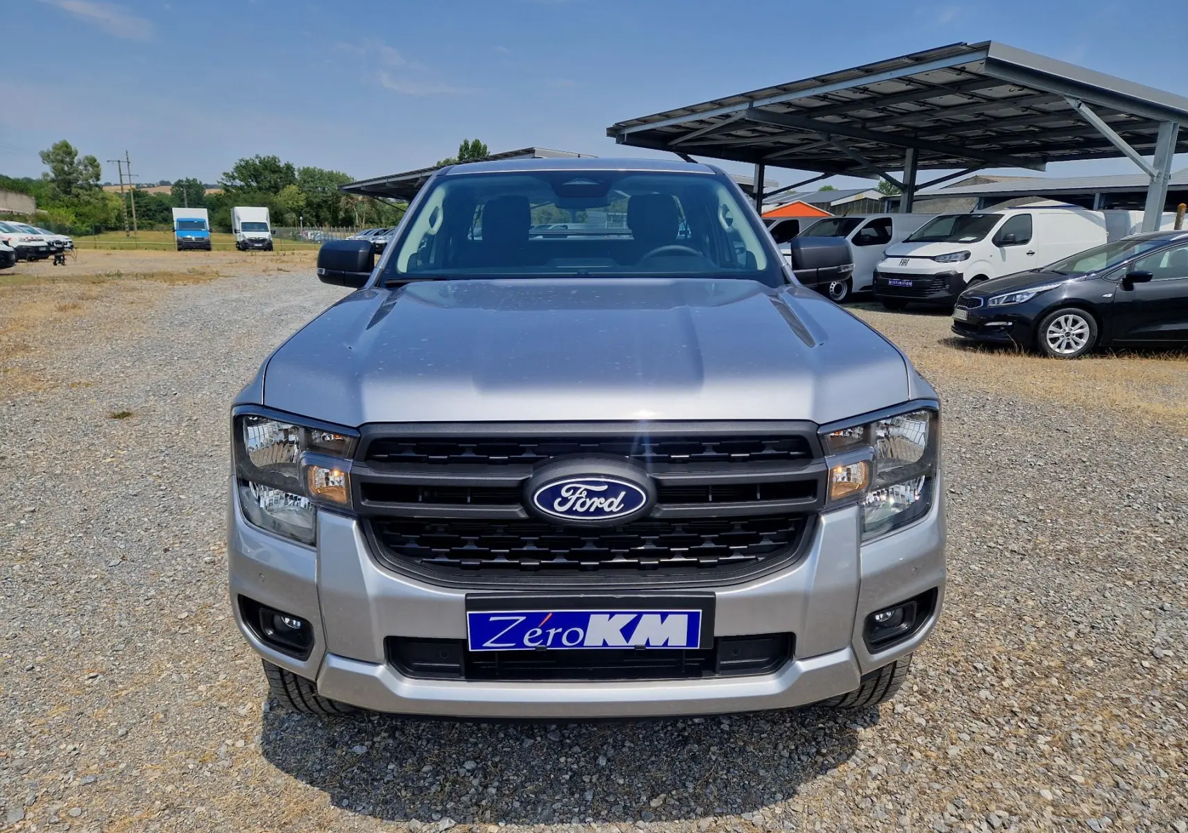 Vue frontale d’un Ford Ranger Super Cabine gris iconic avec calandre noire et plaque d’immatriculation Zero KM visible.