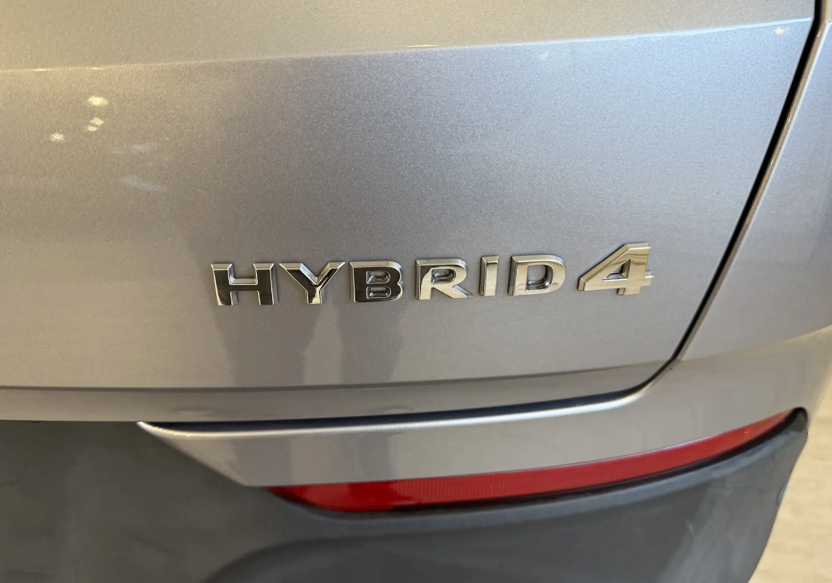 Gros plan sur l'arrière droit gris Himalaya métal d'un Opel Grandland X avec l'inscription Hybrid4 visible.