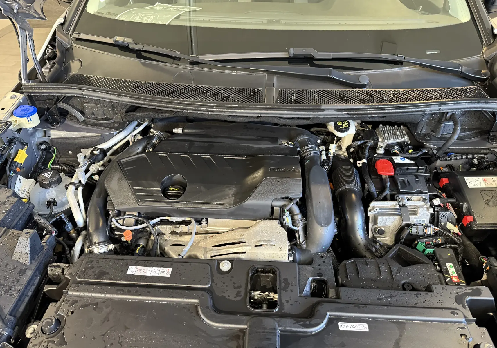 Vue rapprochée du moteur hybride sous capot ouvert de l’Opel Grandland X gris Himalaya 2021.