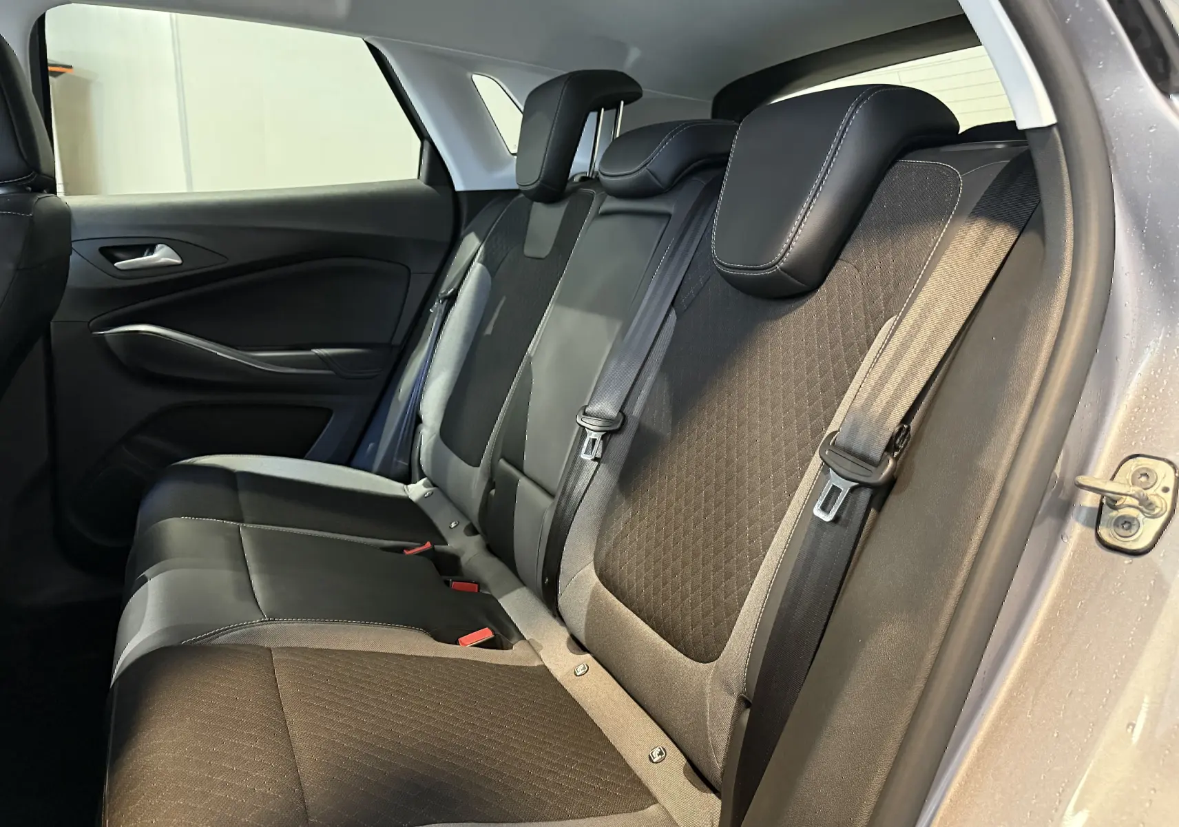 Vue latérale droite des sièges arrière noirs avec surpiqûres blanches de l'Opel Grandland X gris Himalaya 2021.