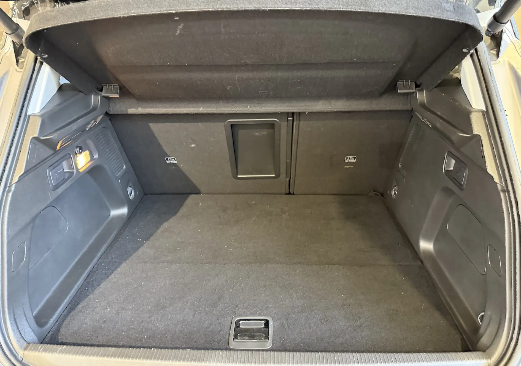 Coffre ouvert vu de l'arrière d'un Opel Grandland X gris Himalaya, montrant l'espace de chargement et les finitions intérieures noires.