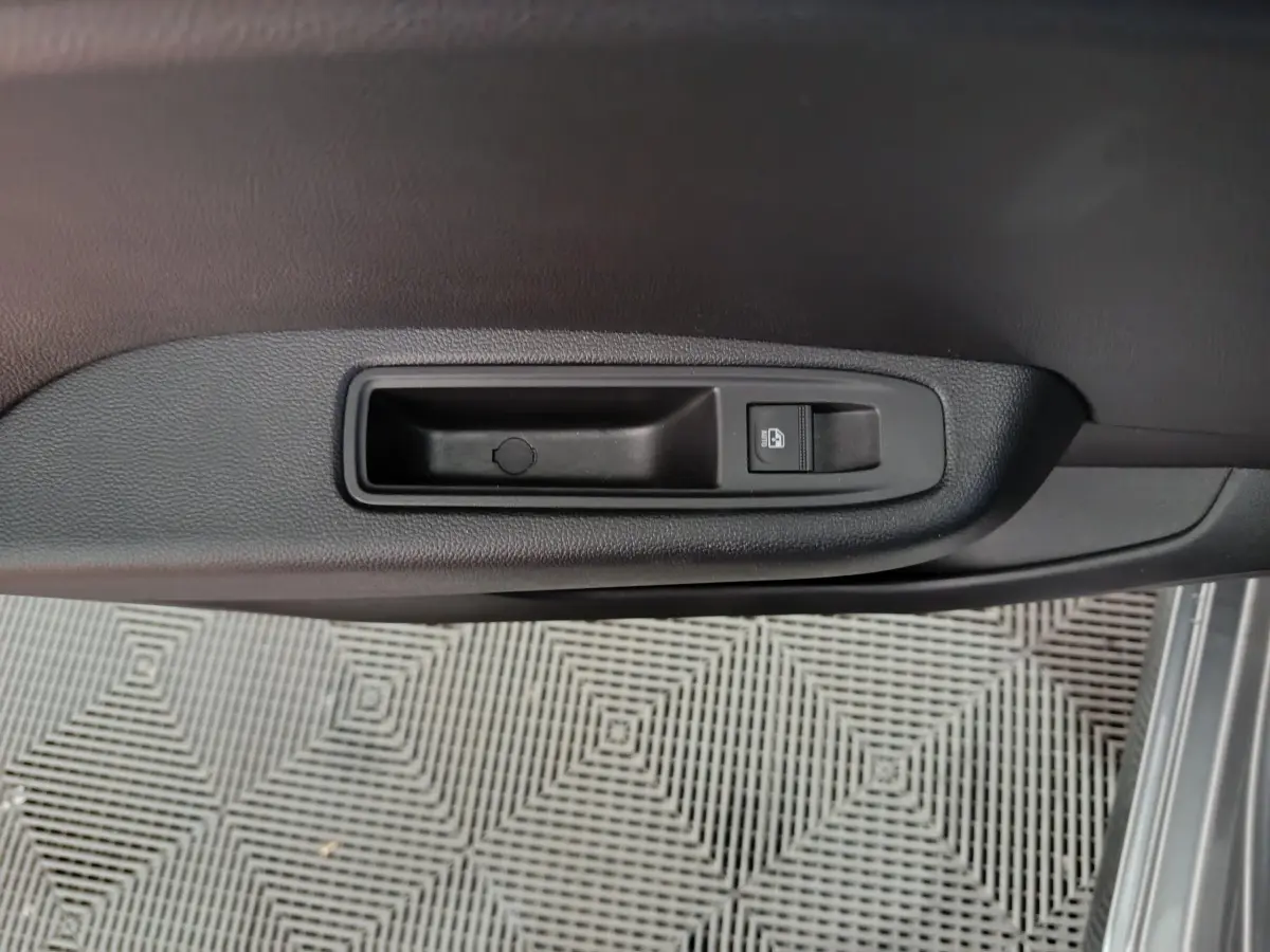 Détail de la poignée intérieure de porte côté conducteur de la Renault Clio gris clair, avec bouton de verrouillage.