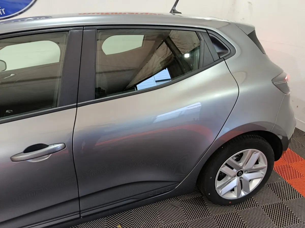 Vue latérale droite sur l'arrière d'une Renault Clio gris clair 2025, avec jante alliage et poignée de porte intégrée.