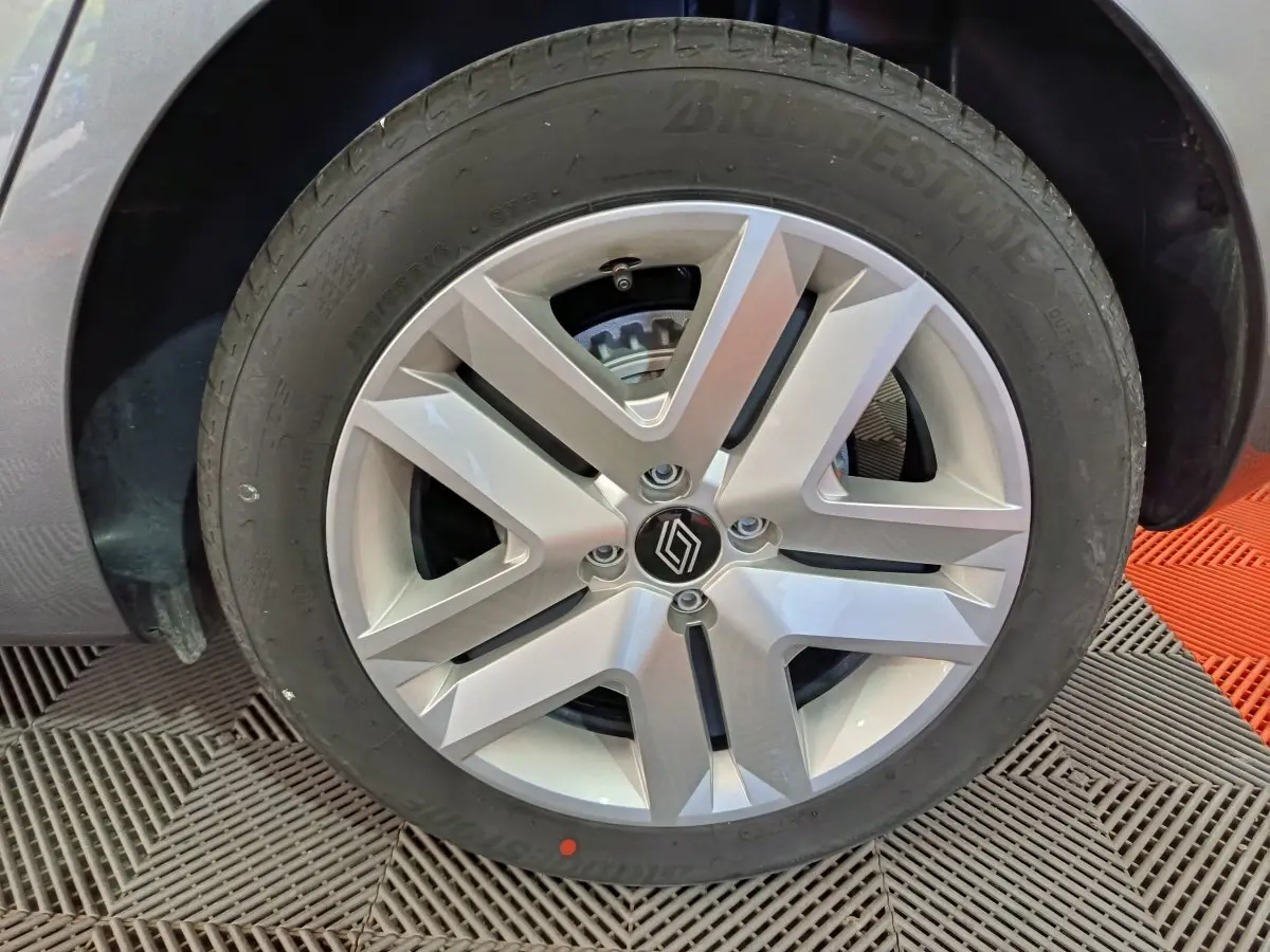 Gros plan sur la roue avant droite de la Renault Clio gris clair, mettant en valeur la jante alliage moderne et le pneu Bridgestone.