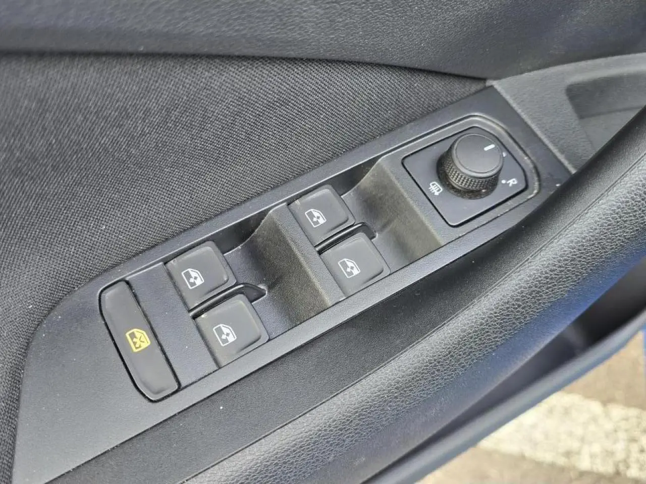 Gros plan sur les commandes des vitres électriques et réglage des rétroviseurs côté conducteur d’une Skoda Kamiq 2025 bleu Racing toit noir.