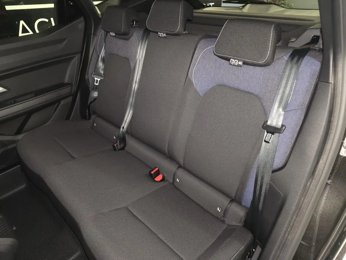 Vue de côté gauche sur la banquette arrière noire et denim bleu du Dacia Duster 1.6 Hybrid 2025 avec ceintures trois points.