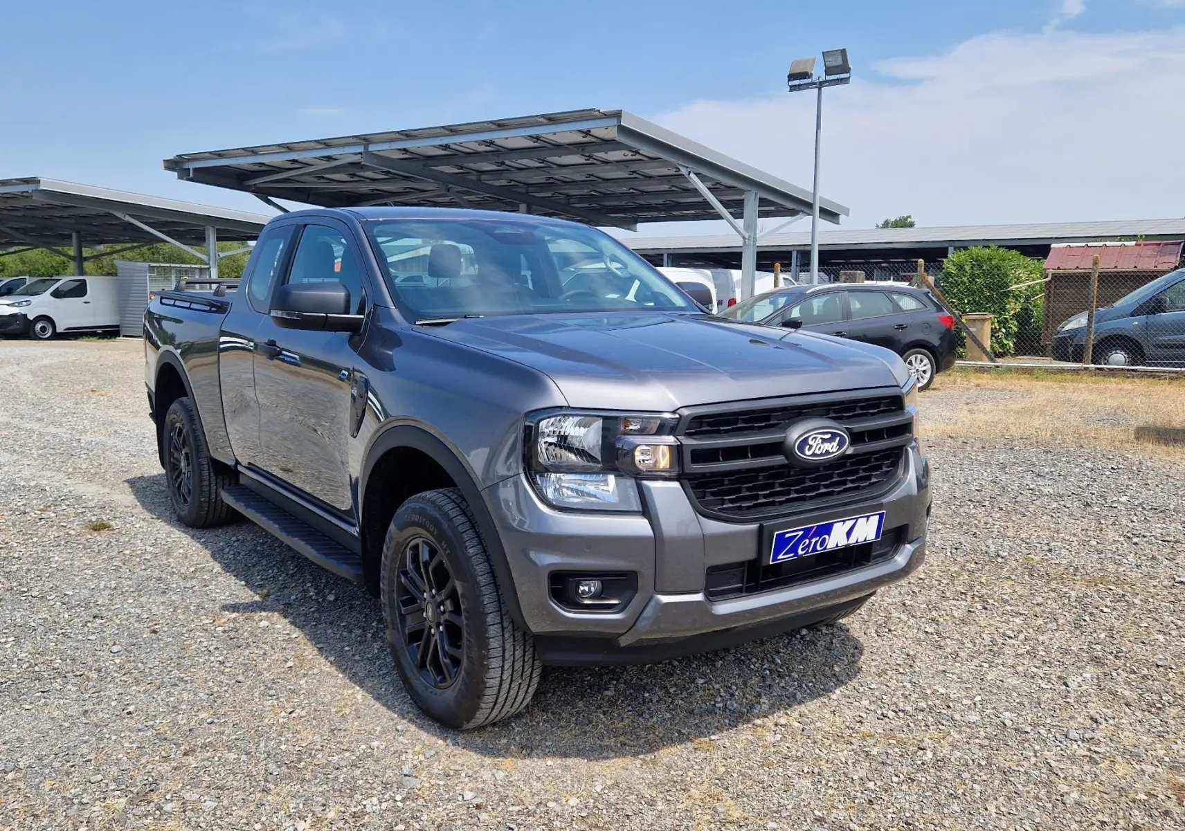 Ford Ranger Super Cabine gris carbone en 3/4 avant droit, avec marchepied et jantes noires visibles.