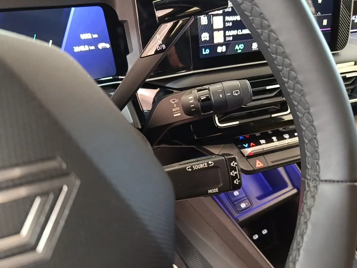 Vue rapprochée du volant et du tableau de bord numérique de la Renault R5 électrique 2024 avec éclairage bleu intérieur.