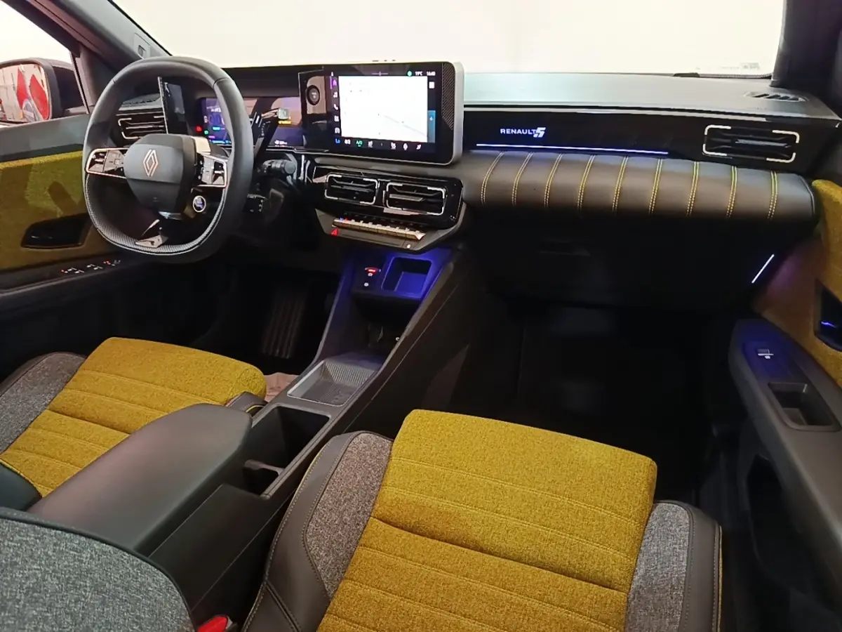 Vue intérieure avant droite de la Renault R5 Iconic 2024 avec sièges moutarde et tableau de bord numérique.