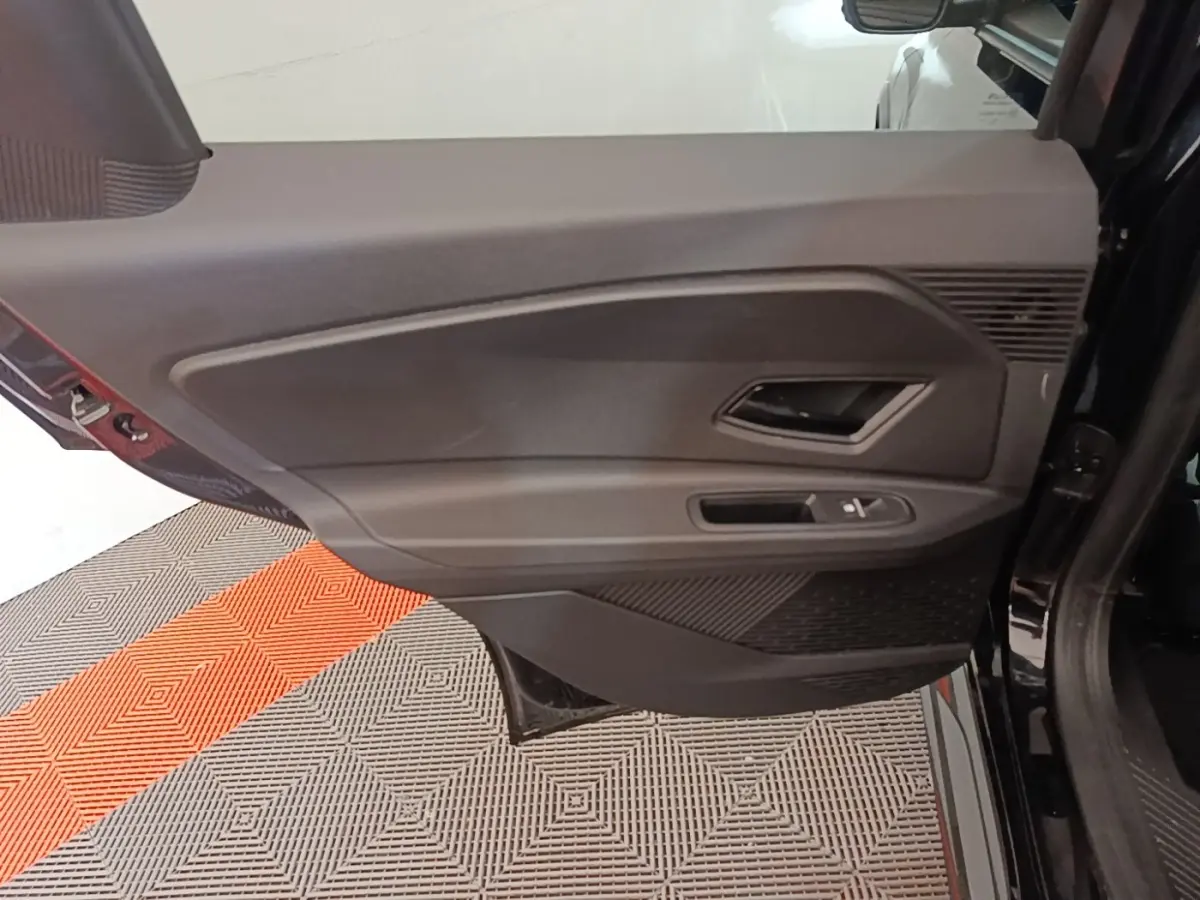 Vue rapprochée de la porte arrière droite noire de la Renault R5 électrique 2024, avec poignée et commande de fenêtre.