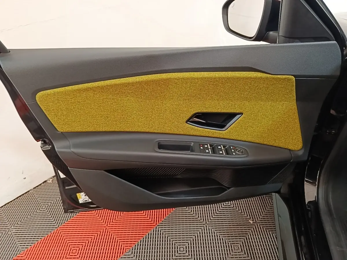 Vue latérale de la porte avant droite de la Renault R5 2024 avec panneau intérieur jaune et commandes électriques.