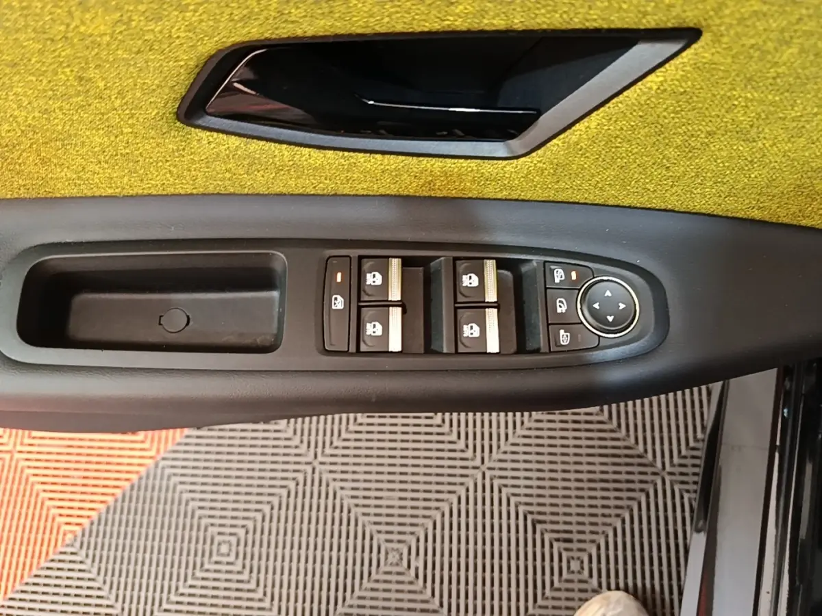 Détail de la commande des vitres et rétroviseurs côté gauche intérieur de la Renault R5 2024 avec garniture jaune.