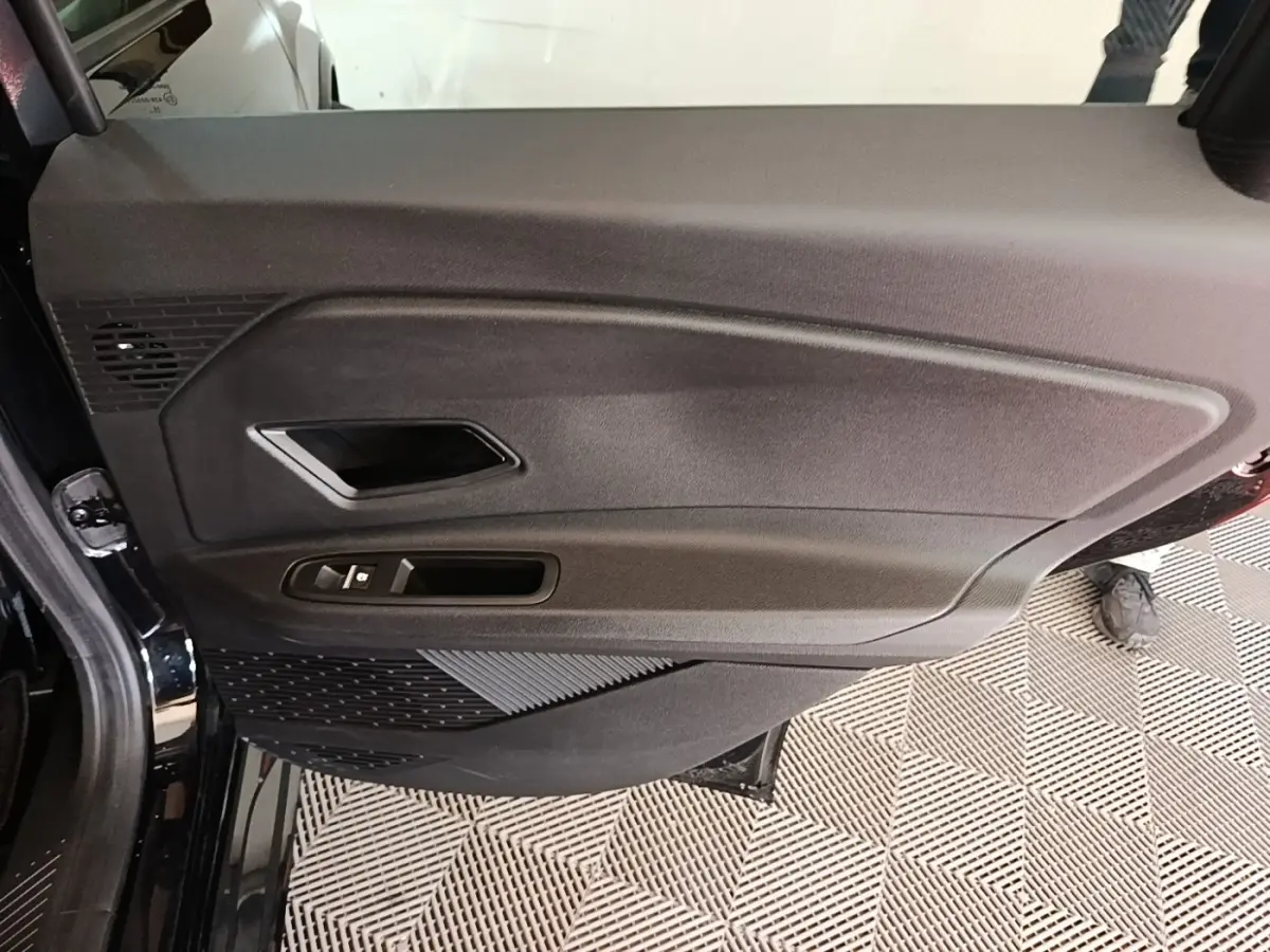 Intérieur côté gauche de la porte avant d'une Renault R5 électrique 2024, avec panneau noir et commandes fenêtres.
