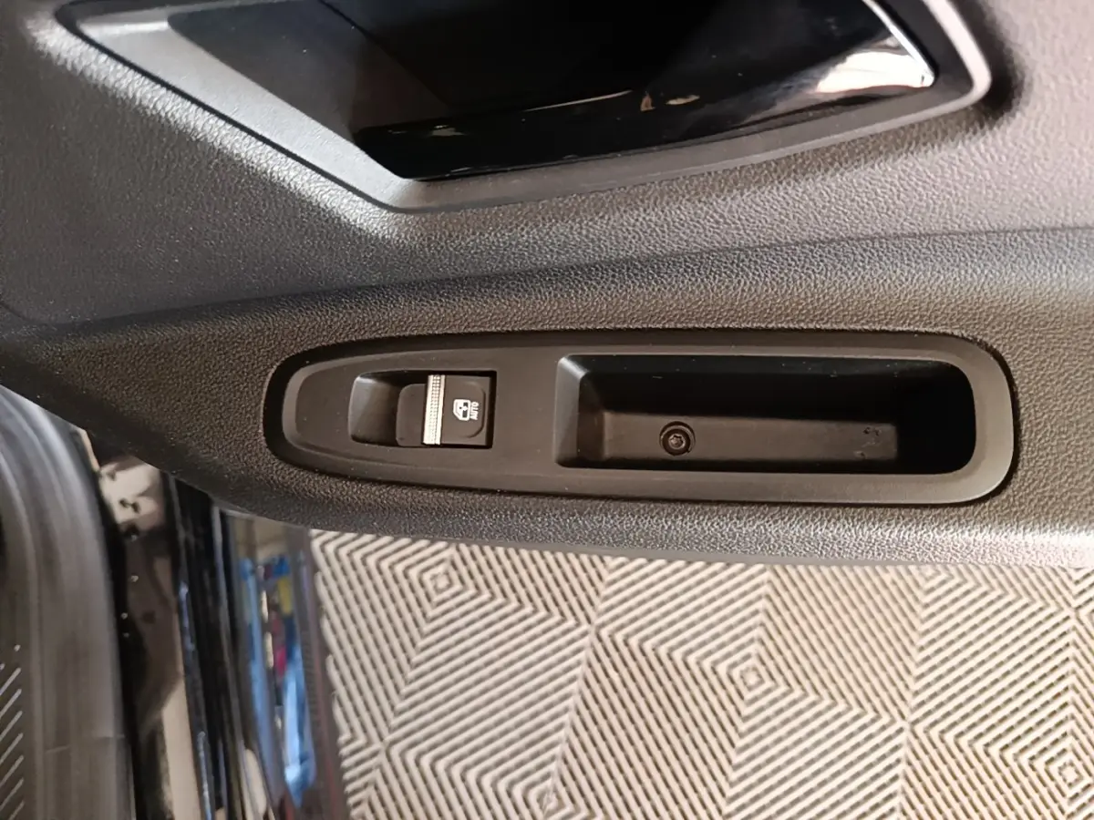 Gros plan sur la commande de lève-vitre côté gauche de la porte intérieure d’une Renault R5 électrique 2024 noire.