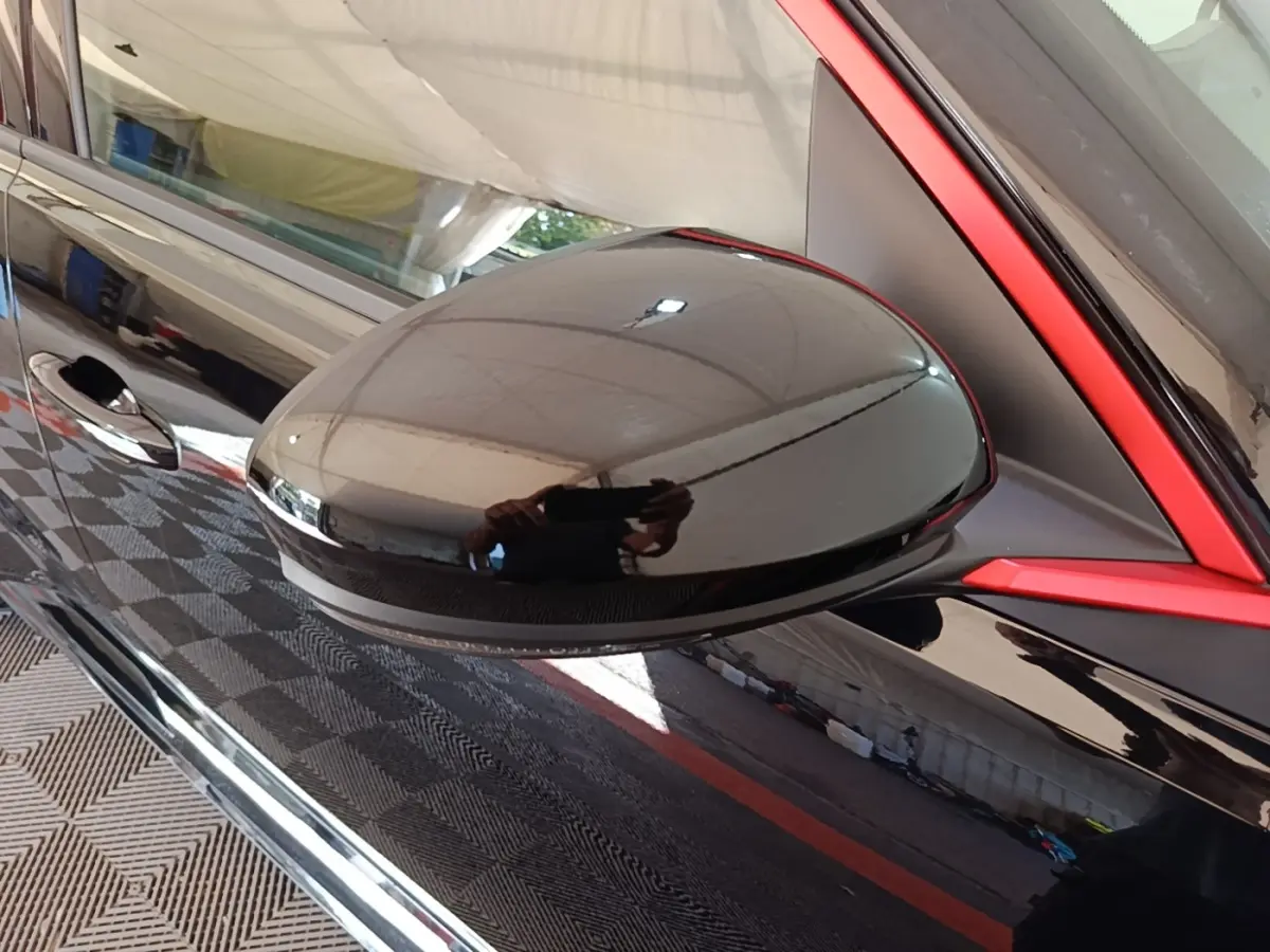 Rétroviseur noir brillant côté gauche de la Renault R5 Iconic 2024 avec cadre rouge distinctif autour de la vitre.
