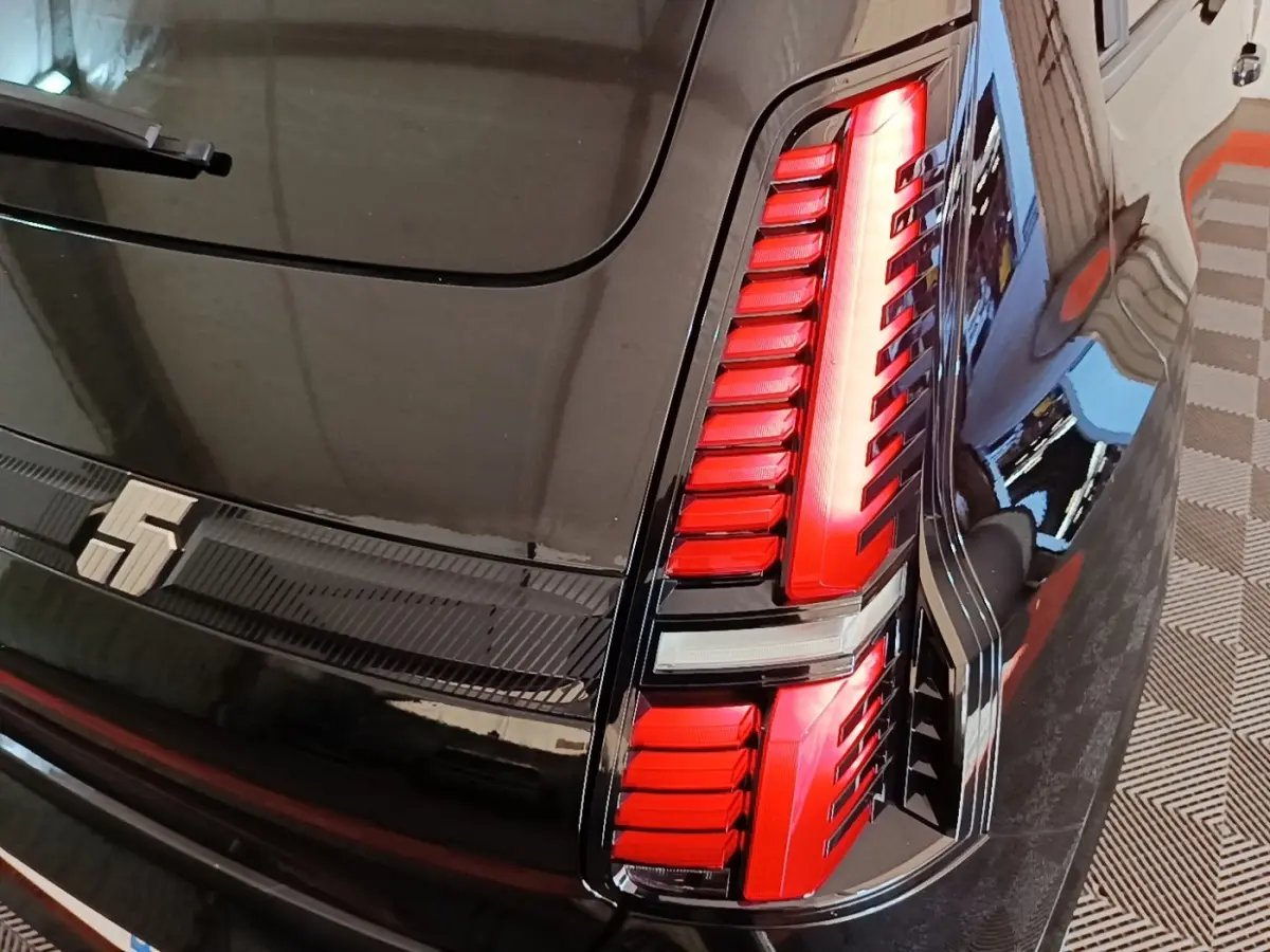 Gros plan sur le feu arrière droit rouge et noir de la Renault R5 Iconic électrique 2024 couleur sombre.