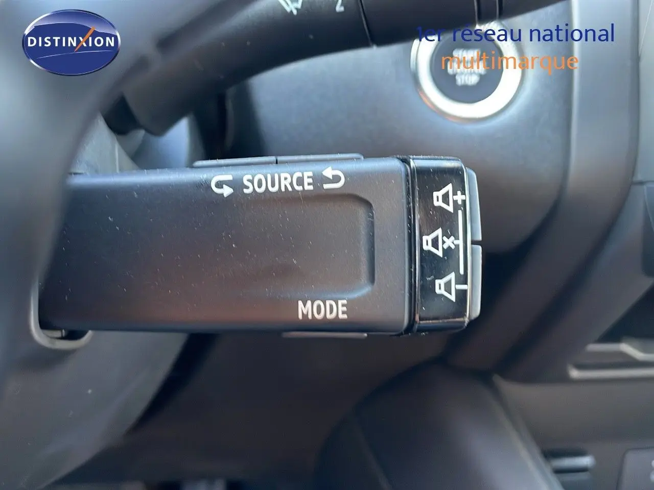 Gros plan sur la commande au volant du Renault Captur blanc nacré, mettant en valeur les boutons source et mode.