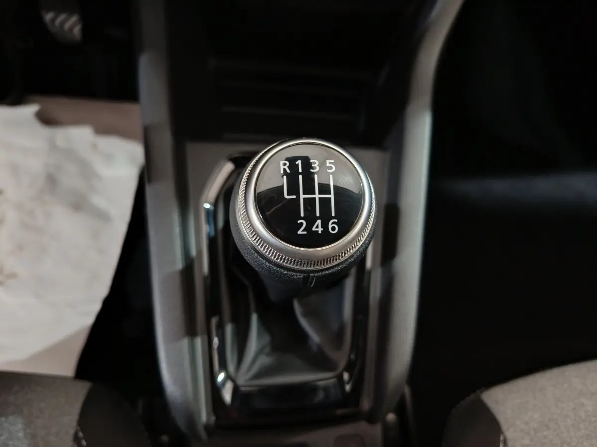 Gros plan sur le levier de vitesses manuel noir de la Renault Clio gris clair, montrant les six rapports et la marche arrière.