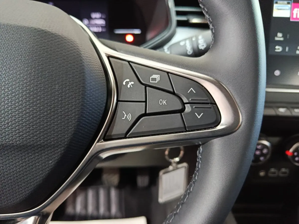 Gros plan sur les commandes multifonctions du volant en cuir synthétique de la Renault Clio gris clair, version Evolution Blue dCi 100.