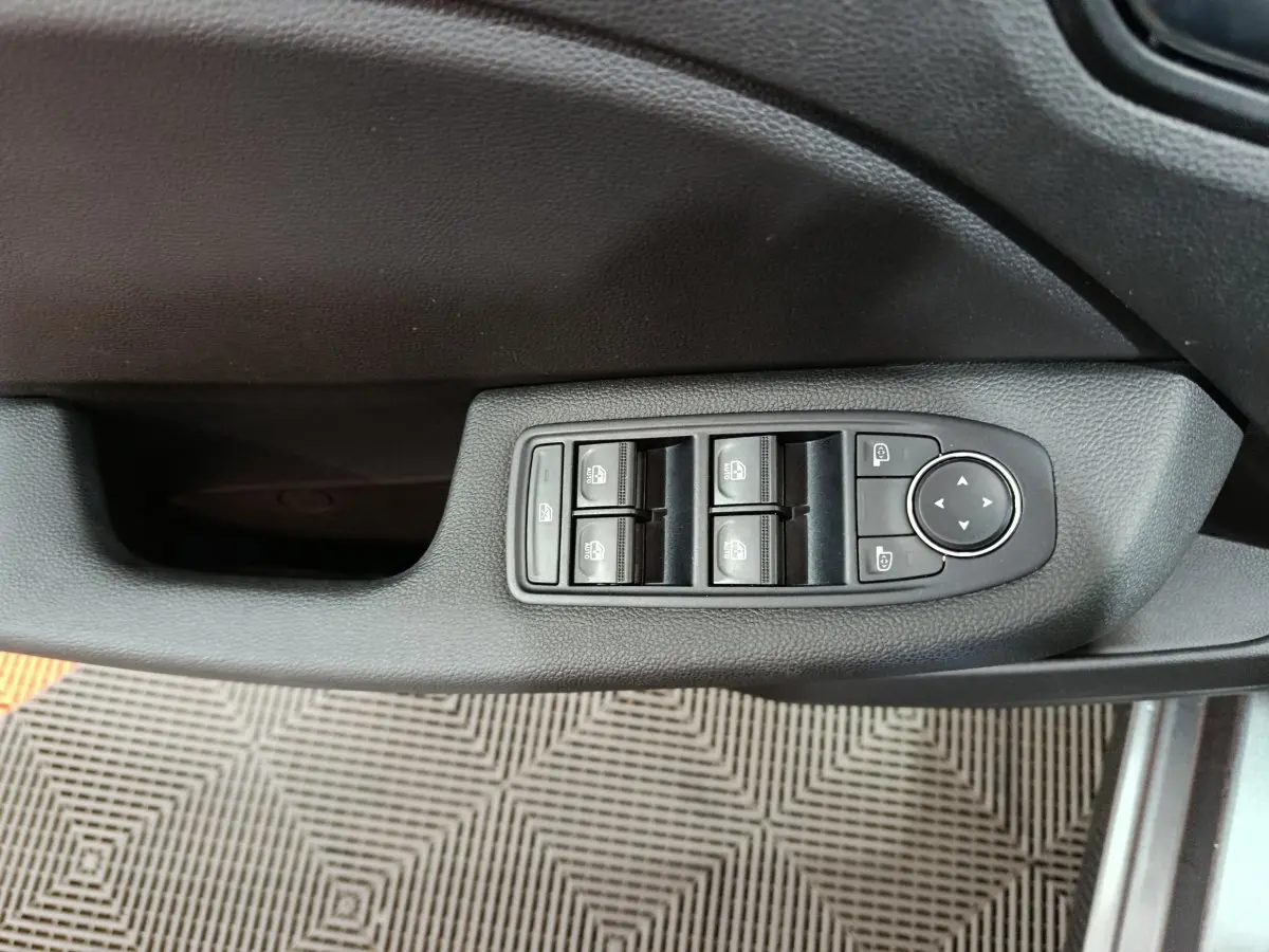 Commande des vitres électriques et réglage des rétroviseurs sur la porte côté conducteur d'une Renault Clio gris clair.