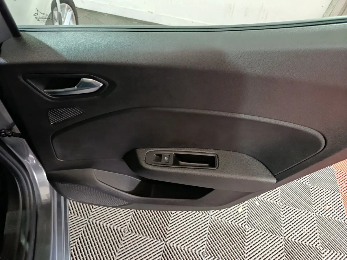 Vue intérieure de la porte côté gauche d'une Renault Clio gris clair, avec poignée argentée et commande de vitre.