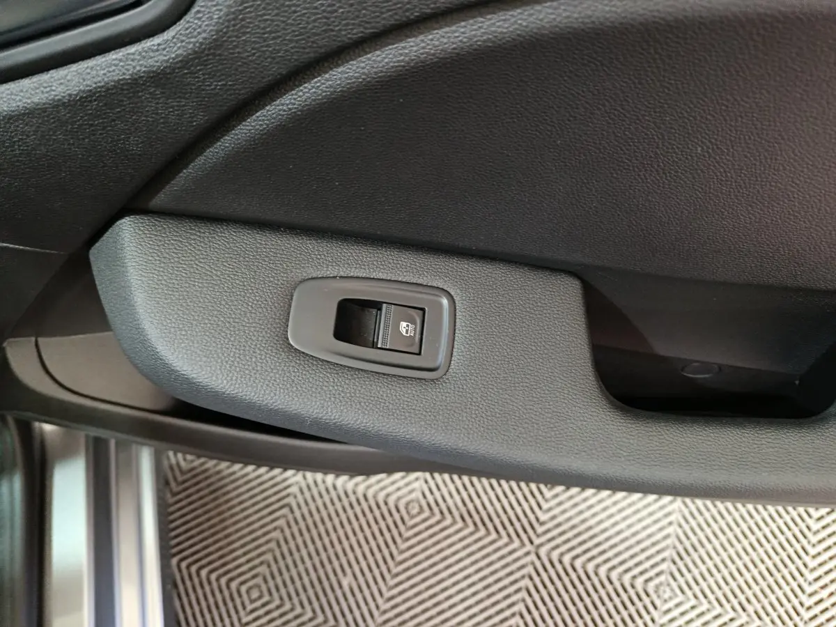 Bouton de commande de lève-vitre sur la portière intérieure côté conducteur d'une Renault Clio gris clair 2025.