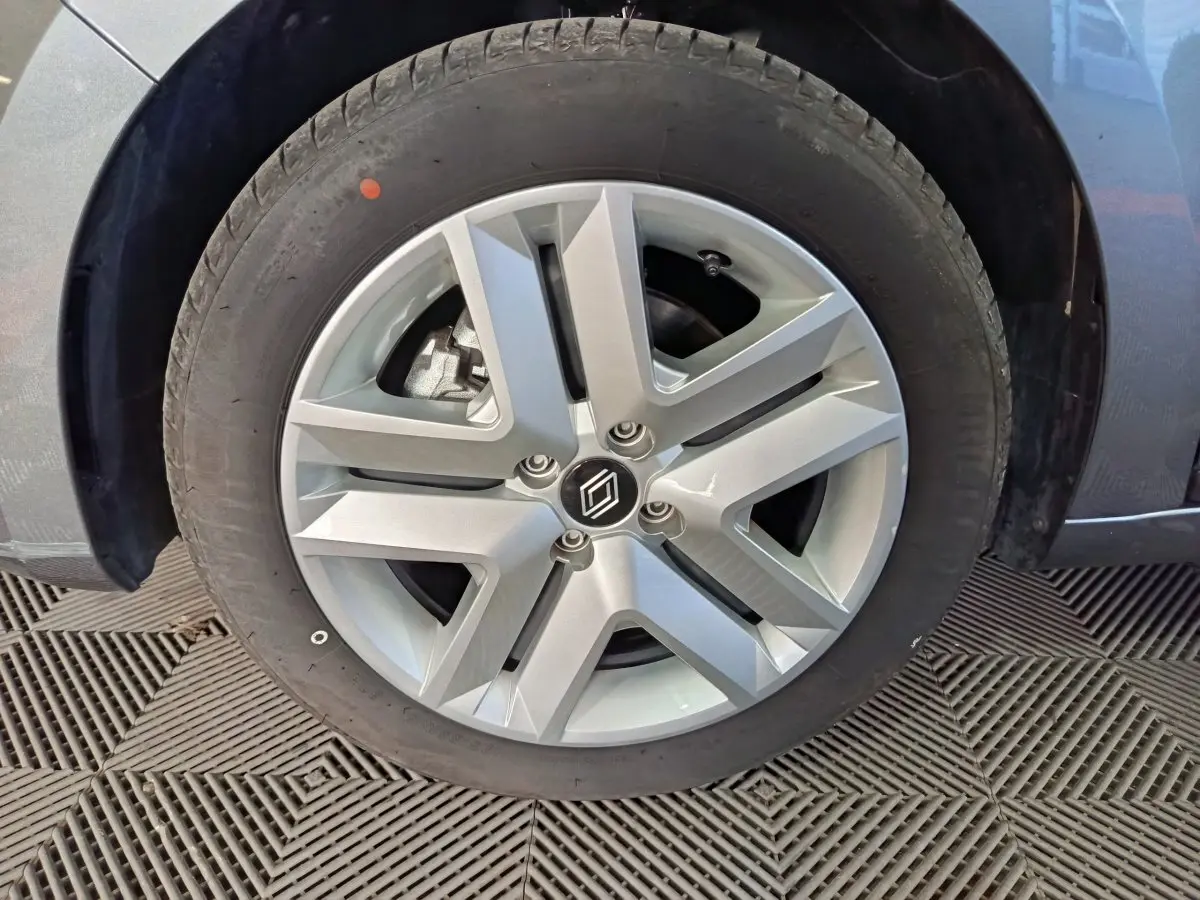 Gros plan sur la roue avant gauche de la Renault Clio gris clair avec jante alliage au design moderne.