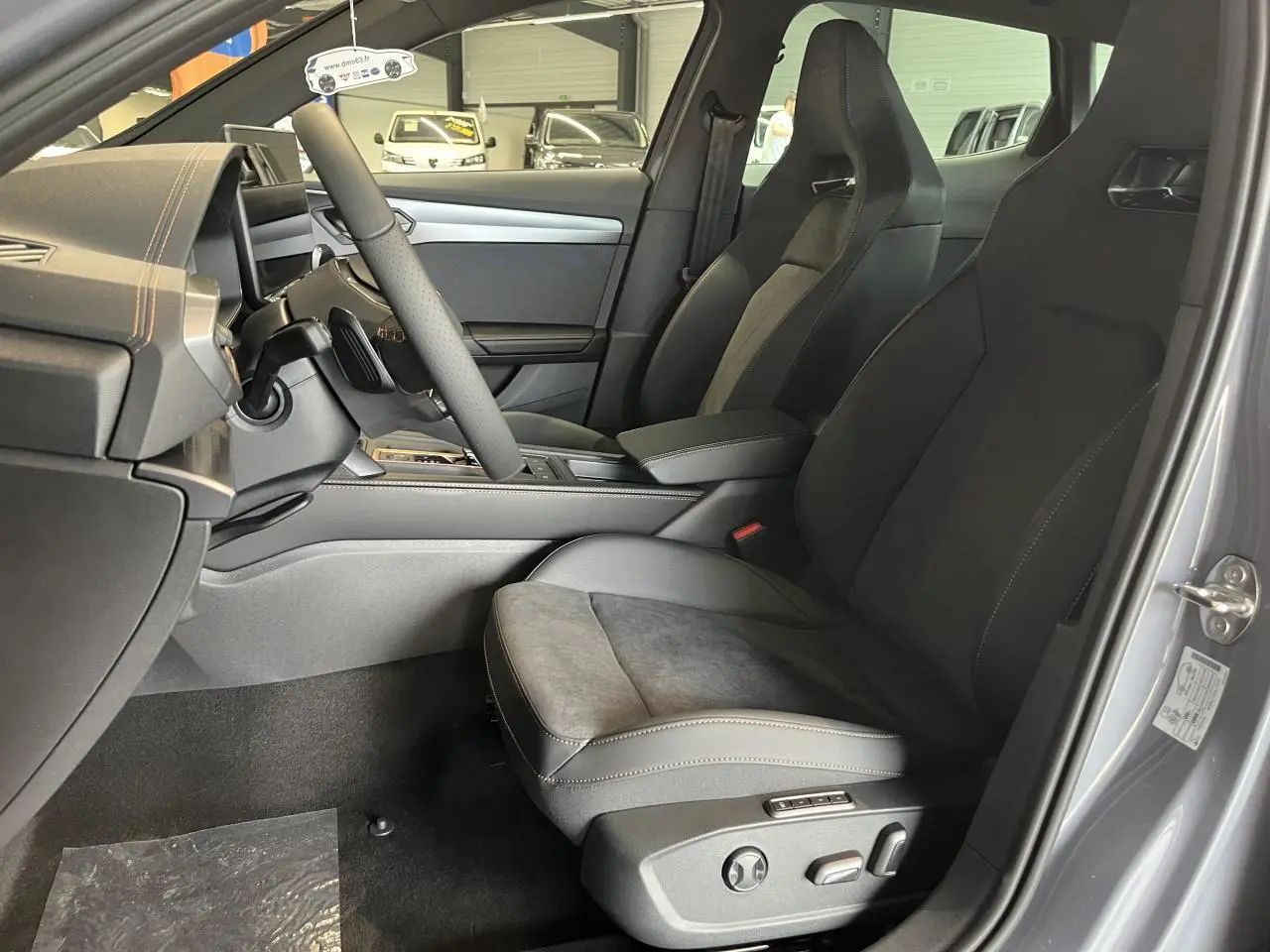 Vue intérieure côté conducteur du CUPRA Formentor 2025 gris clair, avec sièges sport et accoudoir central réglable.