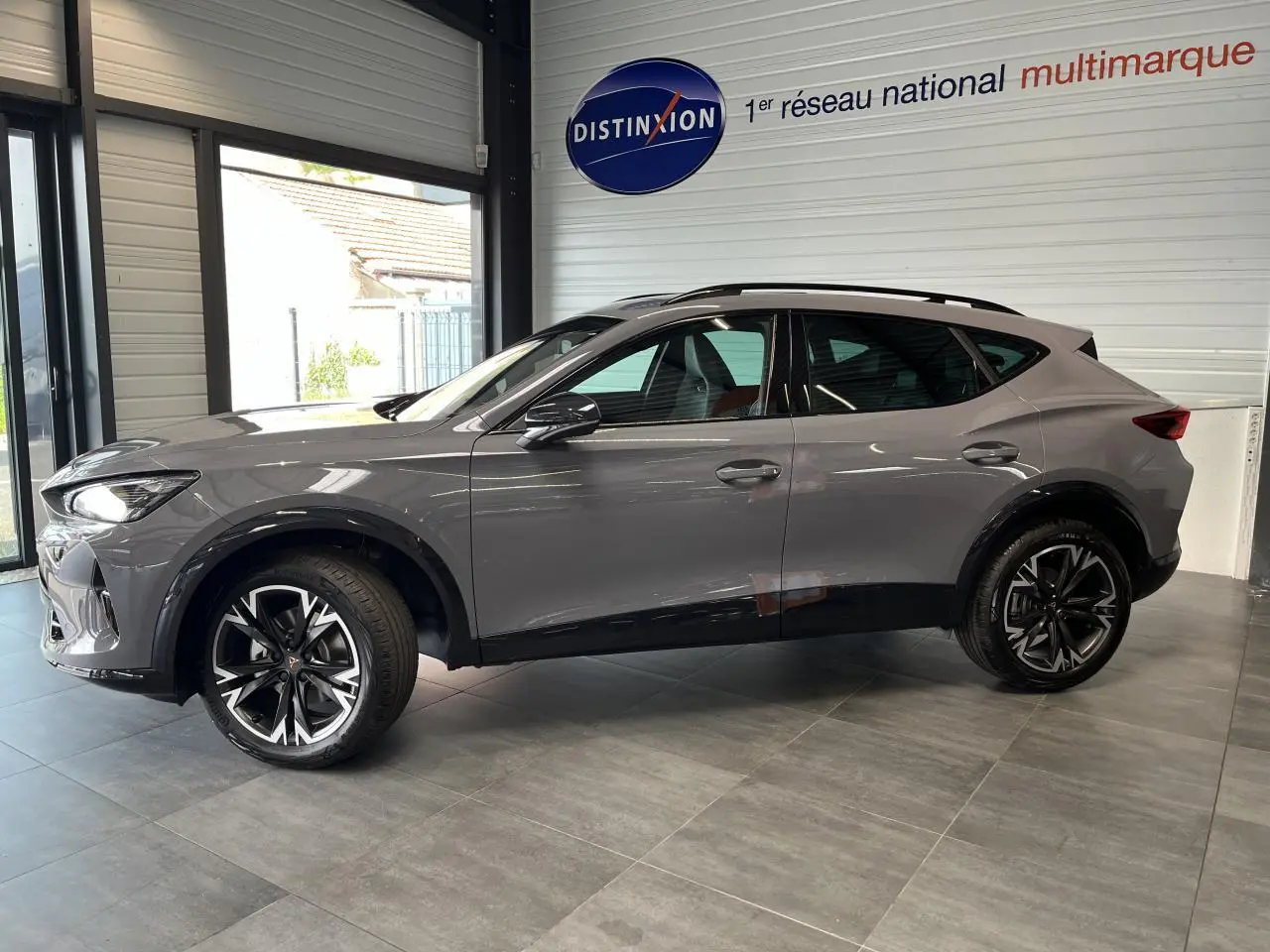 Vue de profil côté gauche d'un CUPRA Formentor gris clair avec jantes alliage noires et détails noirs contrastants.