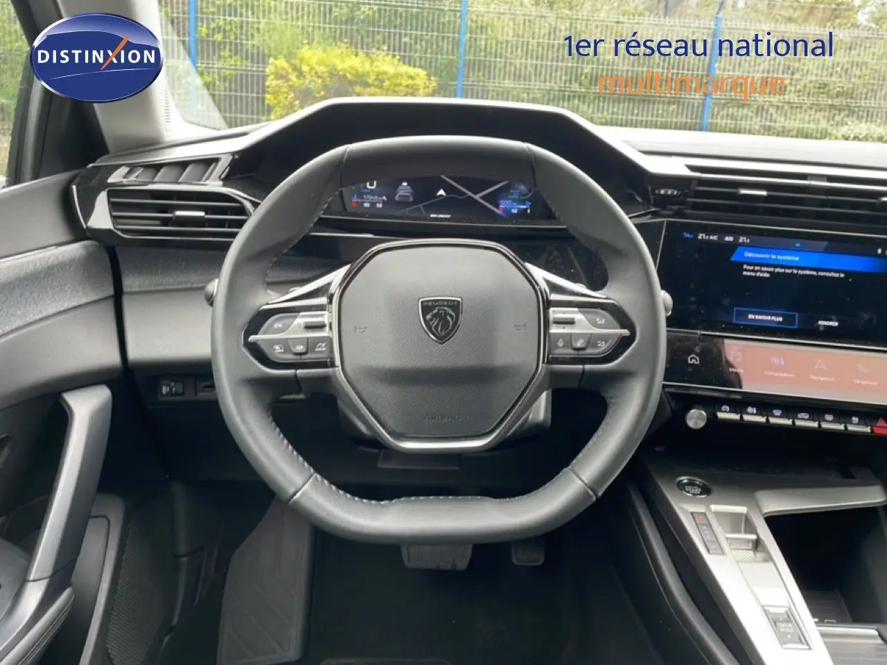 Vue intérieure centrée sur le volant cuir multifonction d’une Peugeot 408 gris selenium, avec tableau de bord digital et écran tactile.