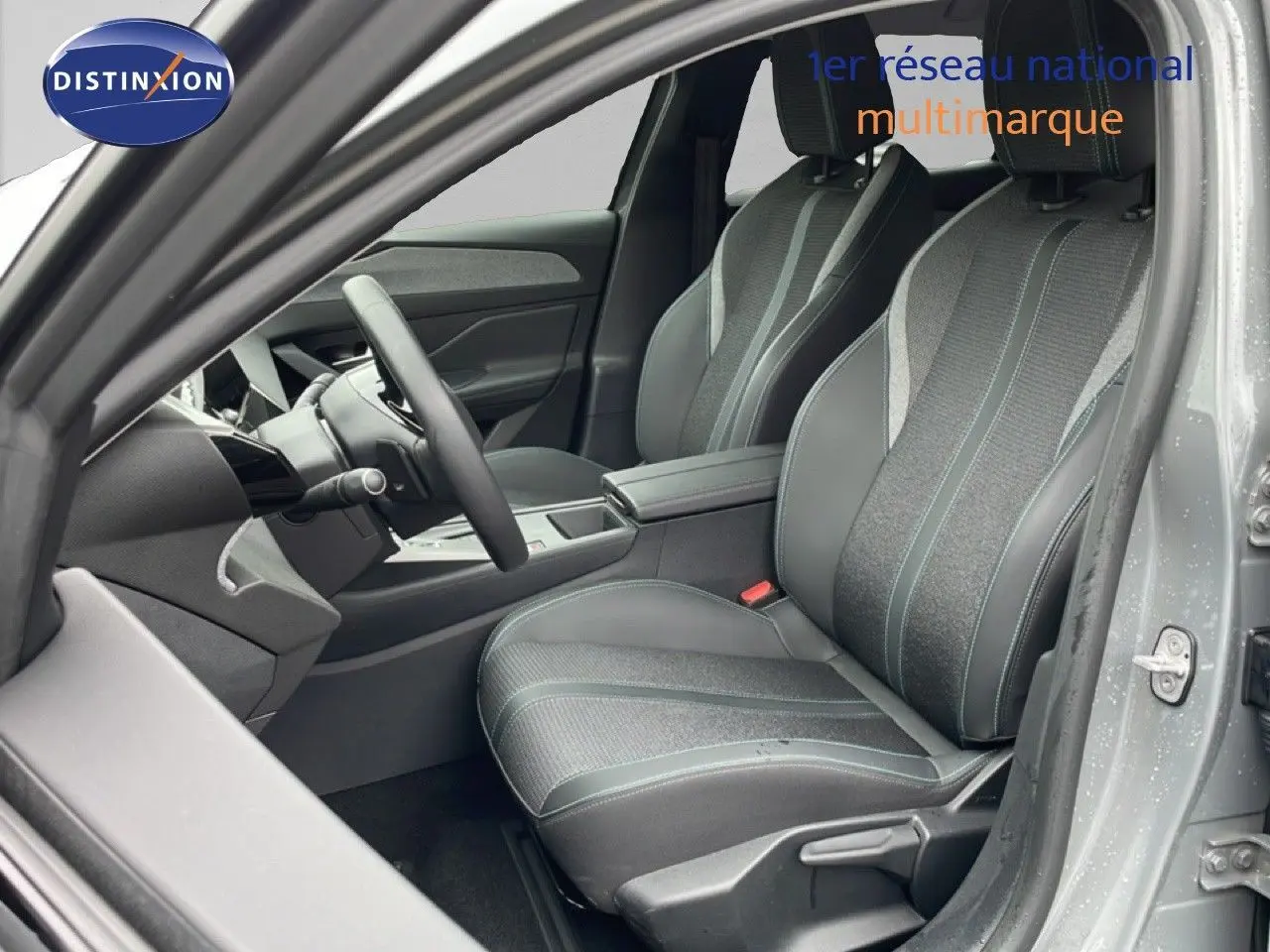Vue intérieure côté conducteur de la Peugeot 408 gris selenium, sièges tissu et cuir avec surpiqûres contrastées.