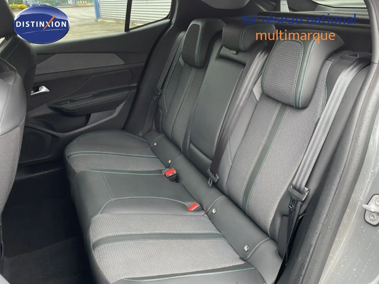 Vue intérieure côté droit montrant la banquette arrière en tissu et cuir gris avec surpiqûres vertes du Peugeot 408 2025.