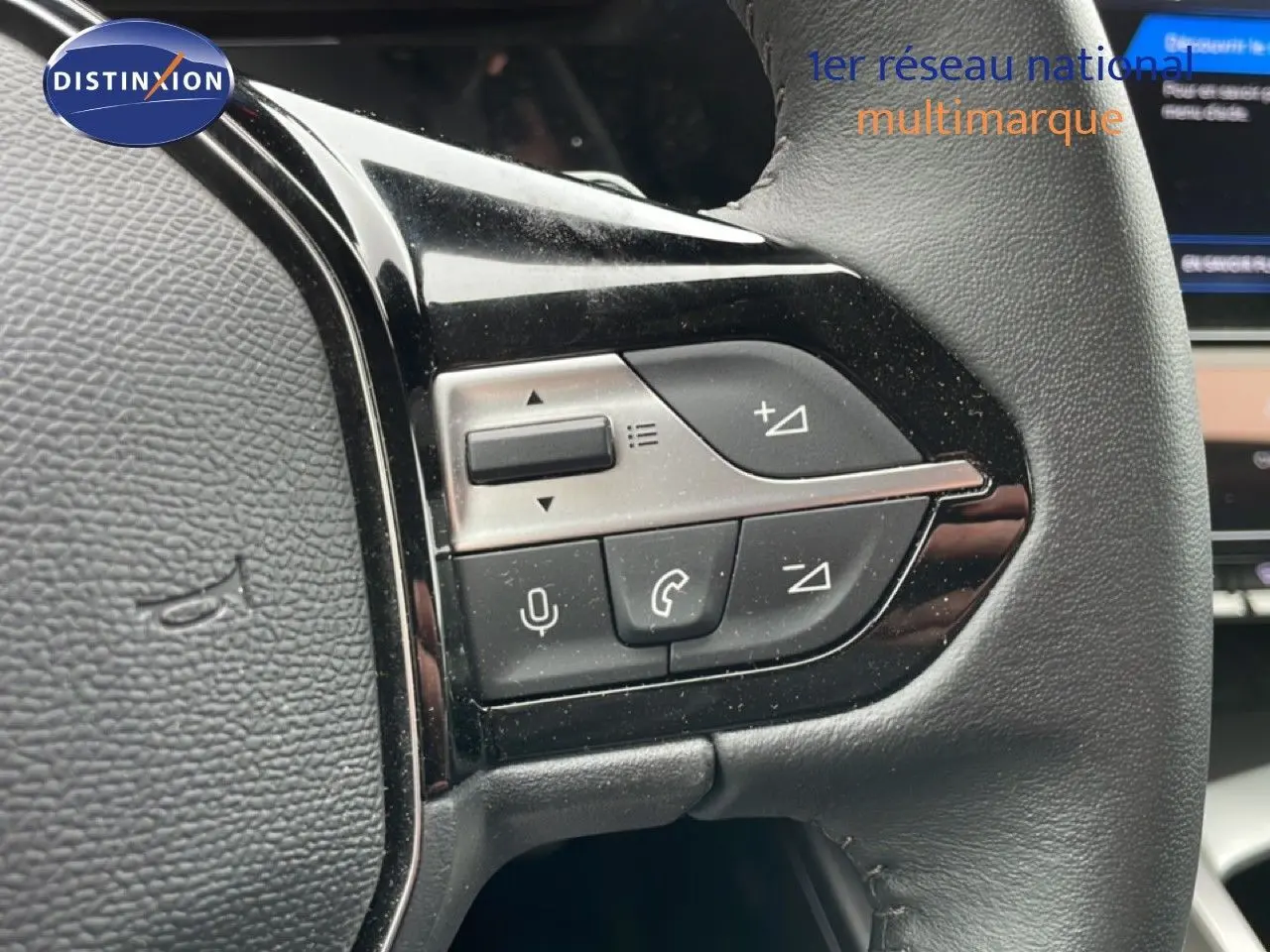 Gros plan sur les commandes multifonctions côté gauche du volant en cuir noir du Peugeot 408 gris Selenium 2025.