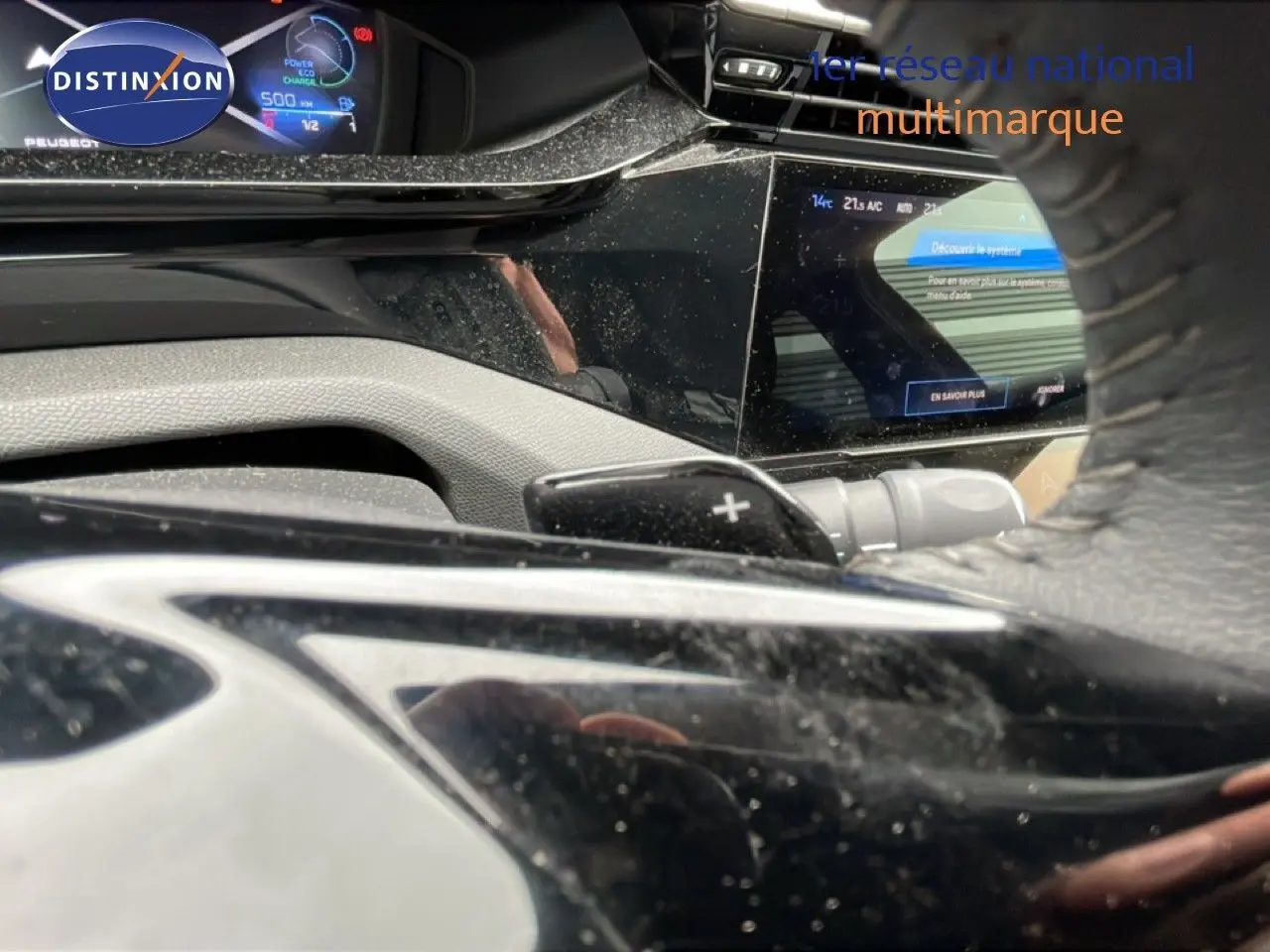Vue rapprochée du tableau de bord et du volant noir de la Peugeot 408 1.2 Hybrid 2025 avec écran digital et palettes au volant.
