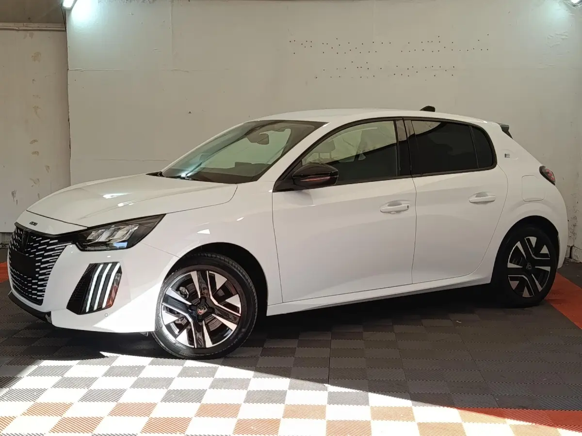 Peugeot 208 électrique blanche vue de profil côté gauche dans un garage avec jantes distinctives bicolores.