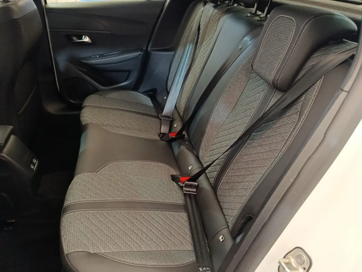 Vue intérieure côté droit sur la banquette arrière grise et noire du Peugeot 208 électrique blanc 2024.