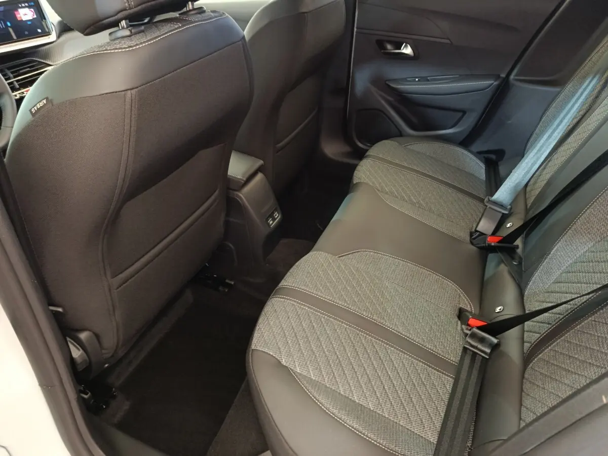 Vue intérieure arrière droite de la banquette tissu et cuir gris foncé de la Peugeot 208 électrique blanche 2024.