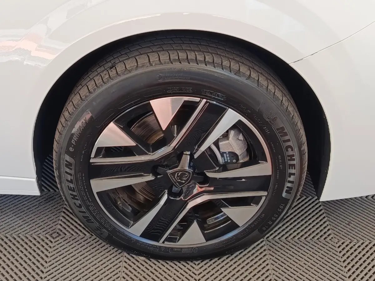 Gros plan sur la roue arrière droite d’une Peugeot 208 électrique blanche, jante alliage bicolore moderne.
