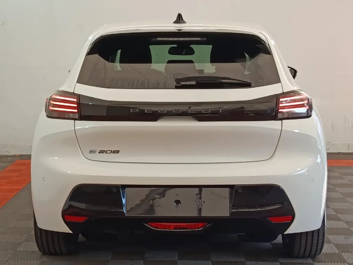 Vue arrière d'une Peugeot 208 électrique blanche 2024 avec feux LED et bande noire distinctive sur le hayon.