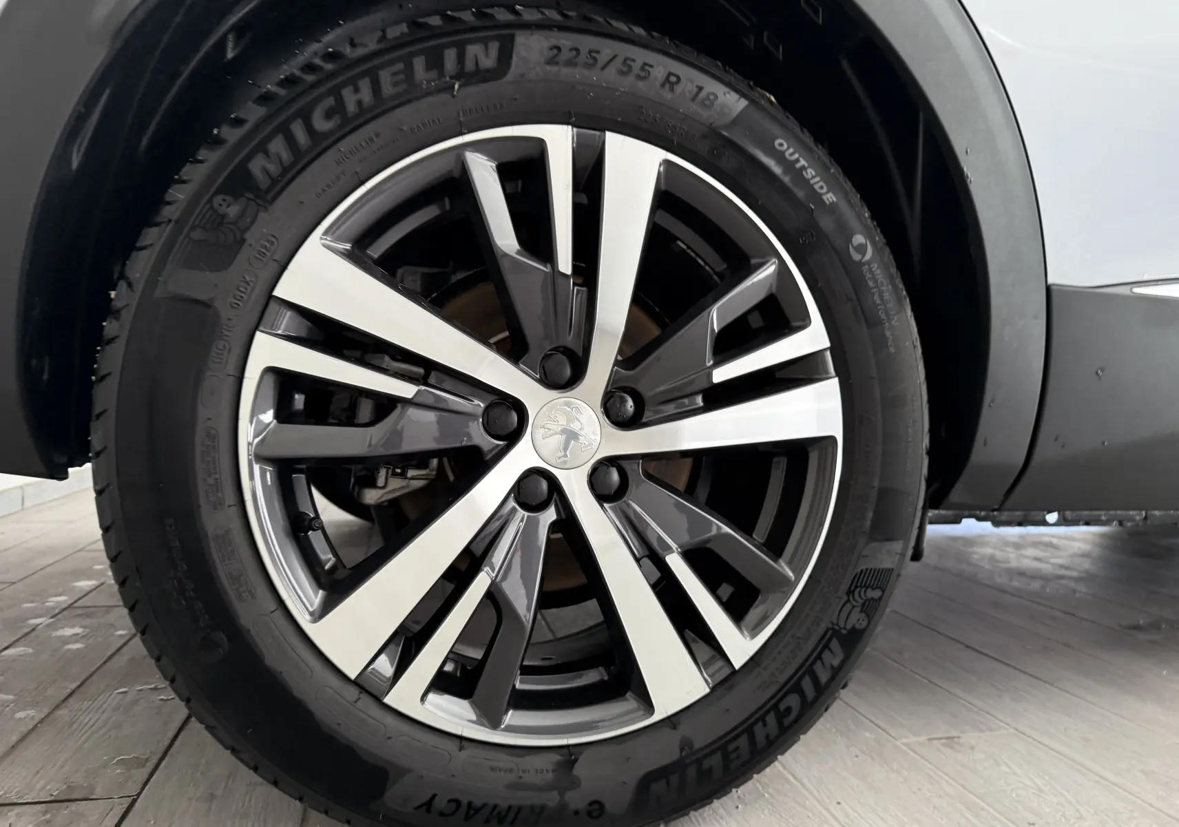 Gros plan sur la roue avant gauche du Peugeot 3008 gris Artense métal, mettant en valeur la jante alliage et le pneu Michelin.