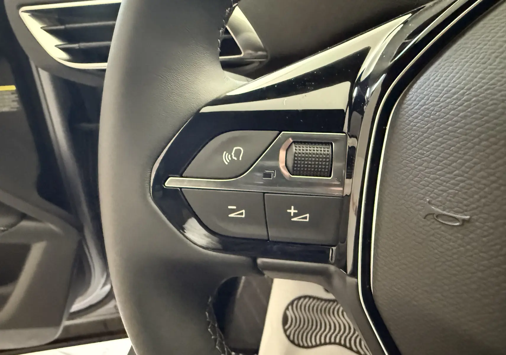 Gros plan sur les commandes gauche du volant noir du Peugeot 3008 gris, avec boutons de volume et activation vocale.