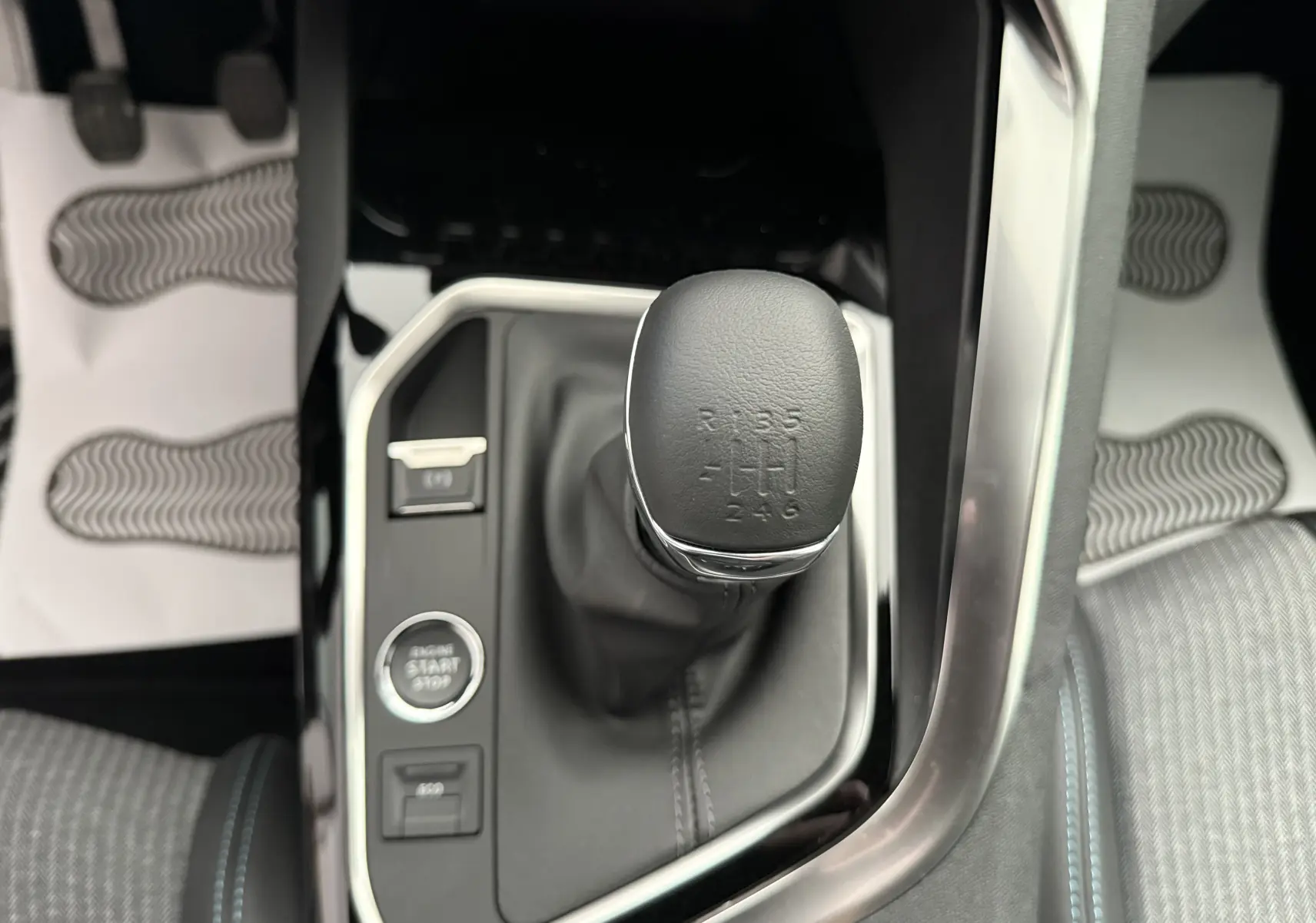 Gros plan sur le levier de vitesse manuel entouré de la console noire et argentée du Peugeot 3008 gris Artense 2023.